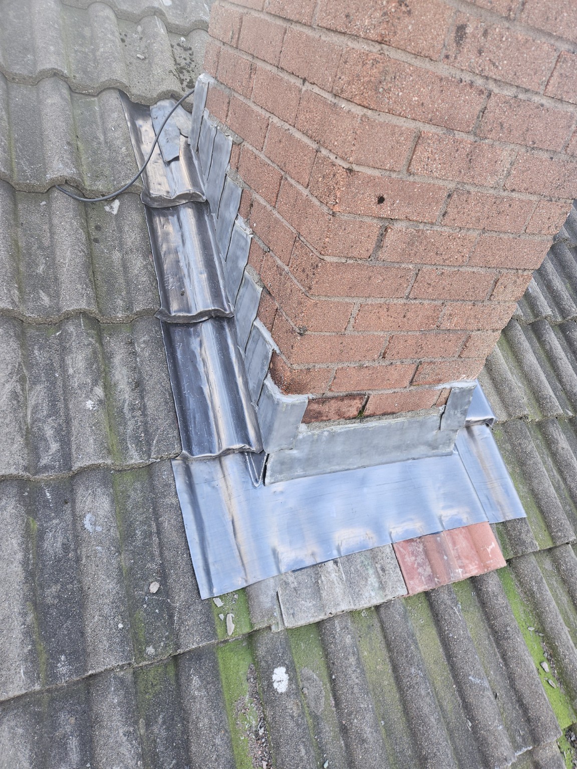 Lead flashing around a brick chimney on a tiled roof